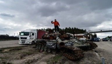 Ukraynalı sivillerden imha edilen Rus tankının önünde zafer pozu